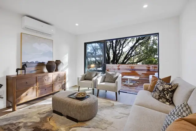 Open-plan kitchen and dining with island bench, rattan stools and light oak flooring